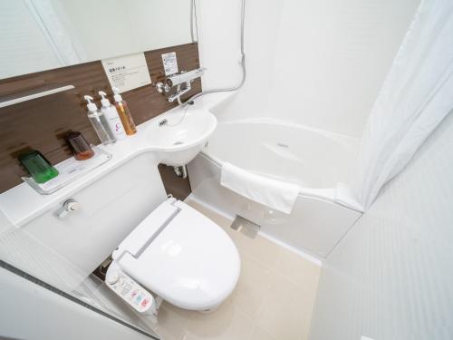 a white bathroom with a toilet and a sink at Super Hotel Premier Akihabara in Tokyo
