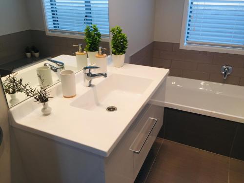 een badkamer met een witte wastafel en een bad bij Stunning Brand New Executive Home in Hastings