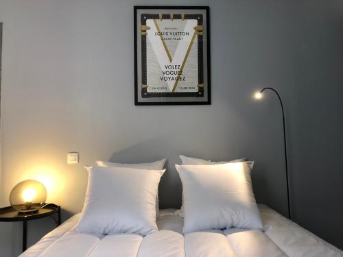 - un lit avec des oreillers blancs et une photo sur le mur dans l'établissement City'IN Appart, à Carcassonne