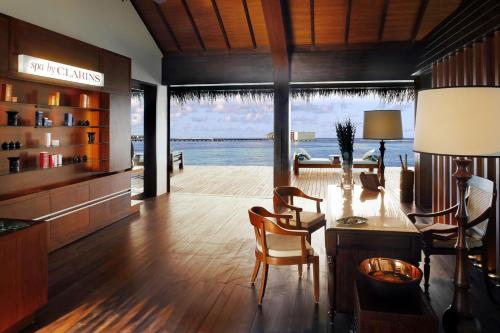 a living room with a table and chairs and the ocean at The Residence Maldives in Gaafu Alifu Atoll