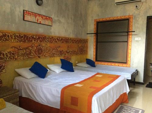 a bedroom with two beds with blue pillows and a mirror at Haritha Holidays in Minneriya