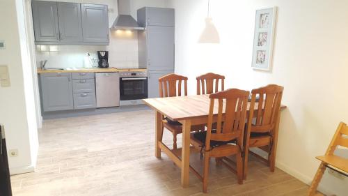 a kitchen with a wooden table and four chairs at Hamburg/Berlin Hamburg App. 106 in Großenbrode