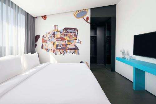 a bedroom with a white bed and a flat screen tv at ARTOTEL Gajahmada Semarang in Semarang