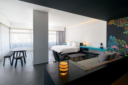 a hotel room with a bed and a living room at ARTOTEL Gajahmada Semarang in Semarang