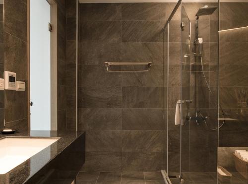 a bathroom with a glass shower with a sink at Listening to the wind B&B in Jiufen