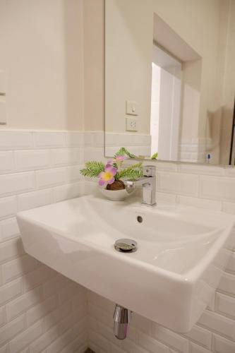 Un lavabo blanco en un baño con espejo. en Lisa'House, en Bangkok