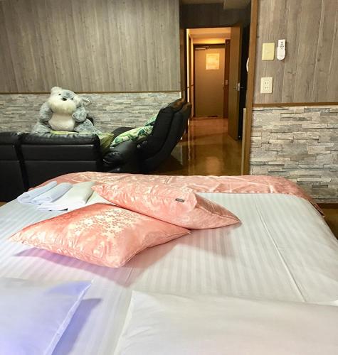 a teddy bear sitting next to a bed in a room at LaForet inn 303  in Hiroshima