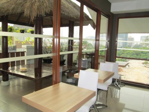a dining room with tables and chairs and windows at Rasuna Mansion in Jakarta