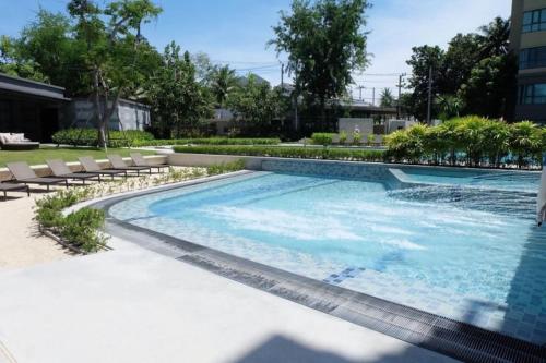 a large swimming pool with chairs next to a building at Rain condo ChaAm HuaHin by AY B311 in Cha Am