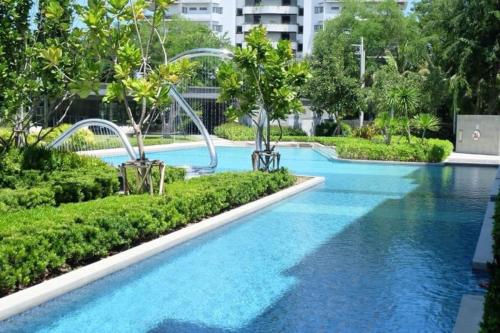 a large swimming pool with blue water and trees at Rain condo ChaAm HuaHin by AY B311 in Cha Am
