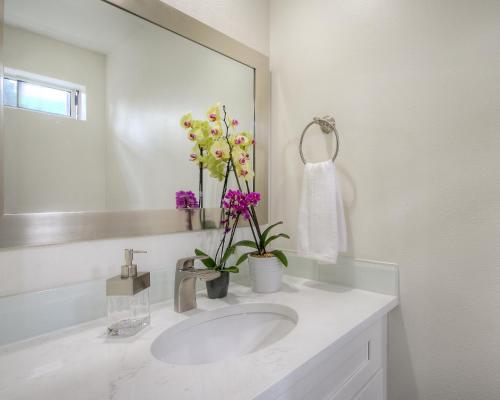 baño con lavabo, espejo y flores en Moon River Suites #5, en North Bend