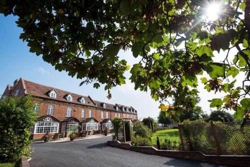 a large brick building with the sun in the sky at Worcester Bank House Hotel Spa & Golf; BW Premier Collection in Worcester