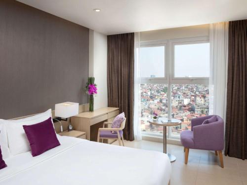 a hotel room with a bed and a large window at Mercure Hai Phong in Hai Phong
