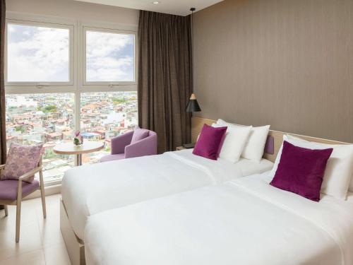 two beds in a hotel room with purple pillows at Mercure Hai Phong in Hai Phong