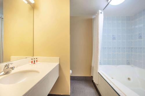 a bathroom with a sink and a bath tub at Baymont by Wyndham McDonough in McDonough