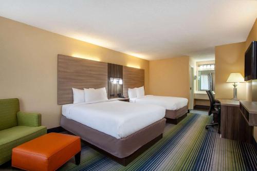 a hotel room with two beds and a chair at Baymont by Wyndham McDonough in McDonough