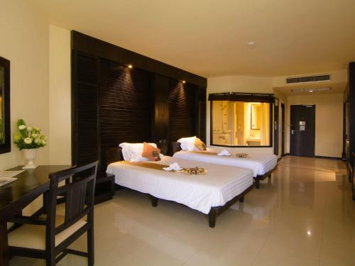 a bedroom with two beds and a table at The Nouveau Chumphon Beach Resort And Golf in Chumphon