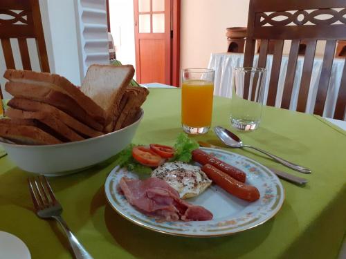 a plate of food on a table with bread and orange juice at Alfred Colonial Bungalow & Spice Garden in Kobbekaduwa