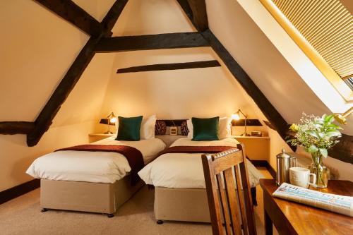 two beds in a attic room with a desk at The Greyhound Inn in Wantage
