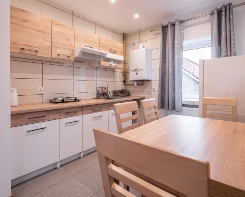 a kitchen with white cabinets and a wooden table at Apartamenty ZYGFRYD 28C/3/2 in Bystrzyca Kłodzka