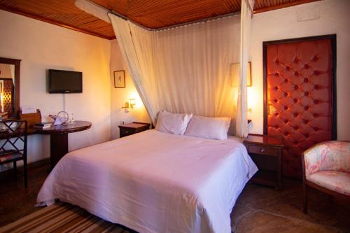 a bedroom with a bed and a chair and a television at Jacaranda Lake Elementeita Lodge in Gilgil