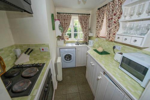 a kitchen with a sink and a stove top oven at Pebble Cottage in Holt