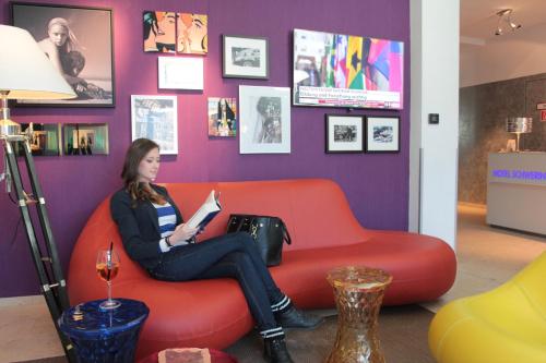 a woman sitting on a red couch in a room at Hotel Schweriner Hof in Stralsund