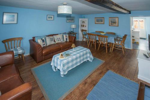 a living room with a couch and a table at Delphinium Cottage in Holt