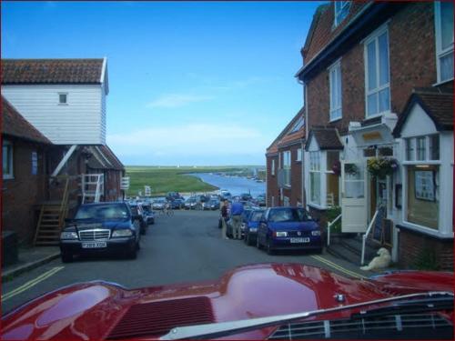 a street with cars parked on the side of the road at Delphinium Cottage in Holt