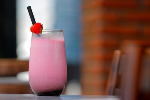 a pink drink with a strawberry on a table at Sagara Candidasa by AHM in Candidasa