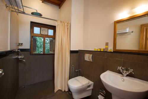 a bathroom with a toilet and a sink and a mirror at Bracknell Forest in Munnar