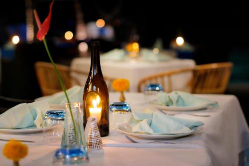 a table with plates and a bottle and a candle at Sagara Candidasa by AHM in Candidasa