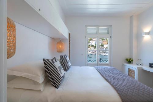 a white bedroom with a large bed and a window at Upper Hydra in Hydra