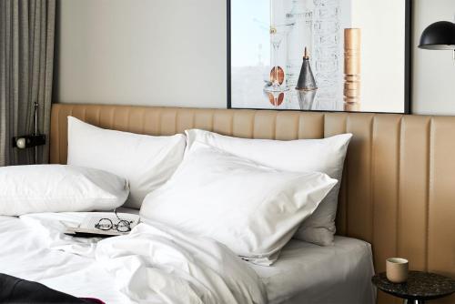 a bed with white sheets and pillows at Veriu Green Square in Sydney