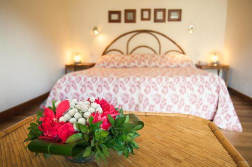 a bedroom with a bed with a table with flowers on it at Tsara Guest House in Fianarantsoa