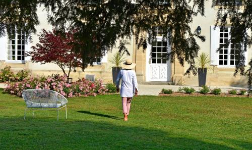 a woman walking in the grass in front of a building at Château Saint Gilles - Bayeux in Guéron