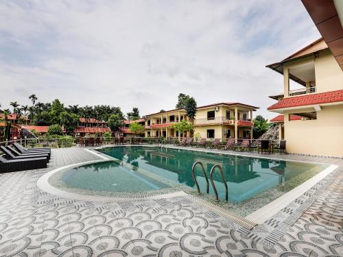 a pool at a resort with chairs and a building at Hotel Wildlife Camp in Sauraha