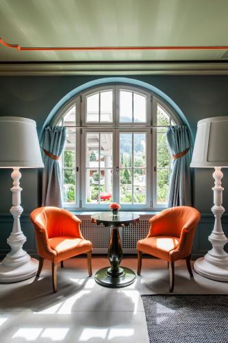 a living room with two chairs and a table and a window at Le Grand Bellevue in Gstaad