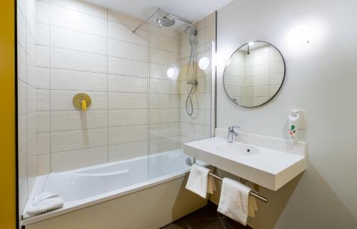 a bathroom with a sink and a tub and a mirror at ibis Styles Paris Meteor Avenue d'Italie in Paris