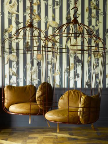 a bird cage with two chairs in a room at Le Grand Bellevue in Gstaad