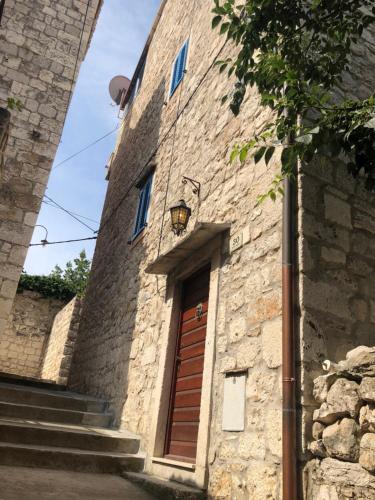 a stone building with a wooden door and stairs at Hvar Old Dalmatian House Junior Suite - Deck 2 in Hvar