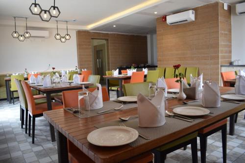 a dining room with tables and chairs with white plates at Hotel Deep Clarks Inn Lucknow in Lucknow
