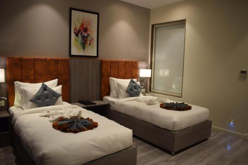 a hotel room with two beds and a mirror at Hotel Deep Clarks Inn Lucknow in Lucknow