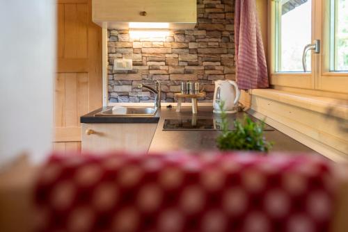 a kitchen with a sink and a stone wall at Camping Danica Cottage Stan in Bohinj