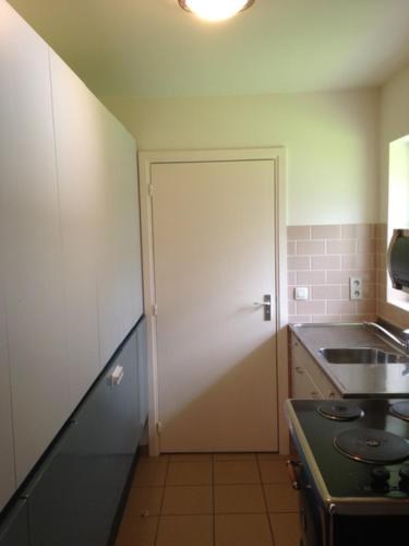 uma cozinha com uma porta que leva a uma cozinha com um lavatório em GOLF APARTMENT em Schilde