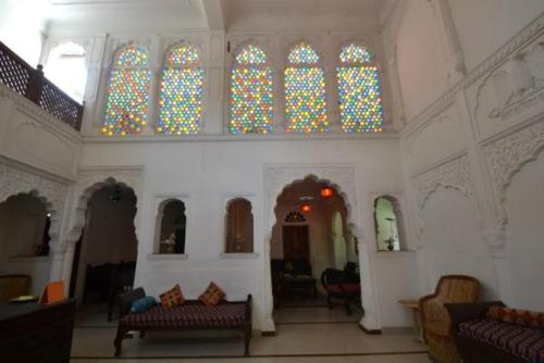 a living room with chairs and stained glass windows at Rawla Mrignayani Palace in Jaipur