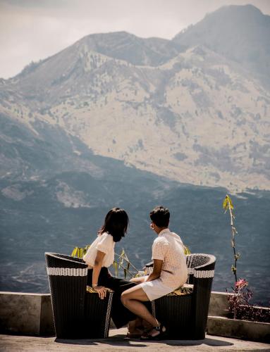 a man and woman sitting on chairs looking at the mountains at Ayodya Batur Villa in Kintamani