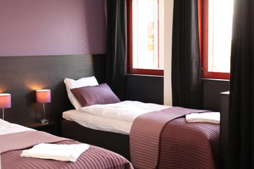 a hotel room with two beds and two windows at Nacka Stadshotell in Nacka