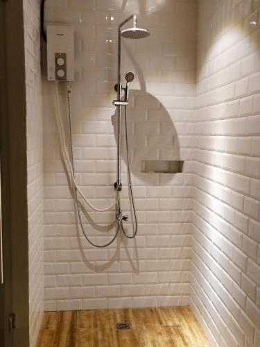 a shower with a hose in a white tiled bathroom at The Hub District Garden Suites in Manila