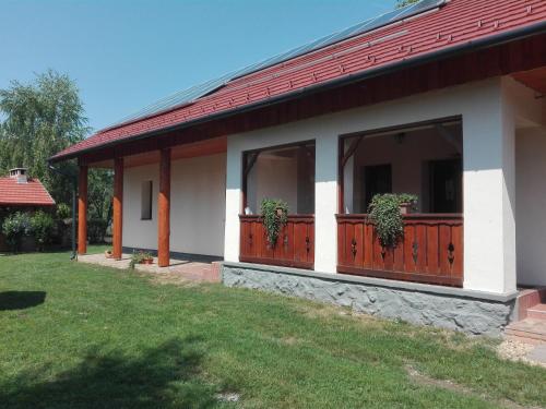 ein Haus mit einer Veranda mit zwei Topfpflanzen darauf in der Unterkunft Zergeboglár Vendégház in Szilvásvárad